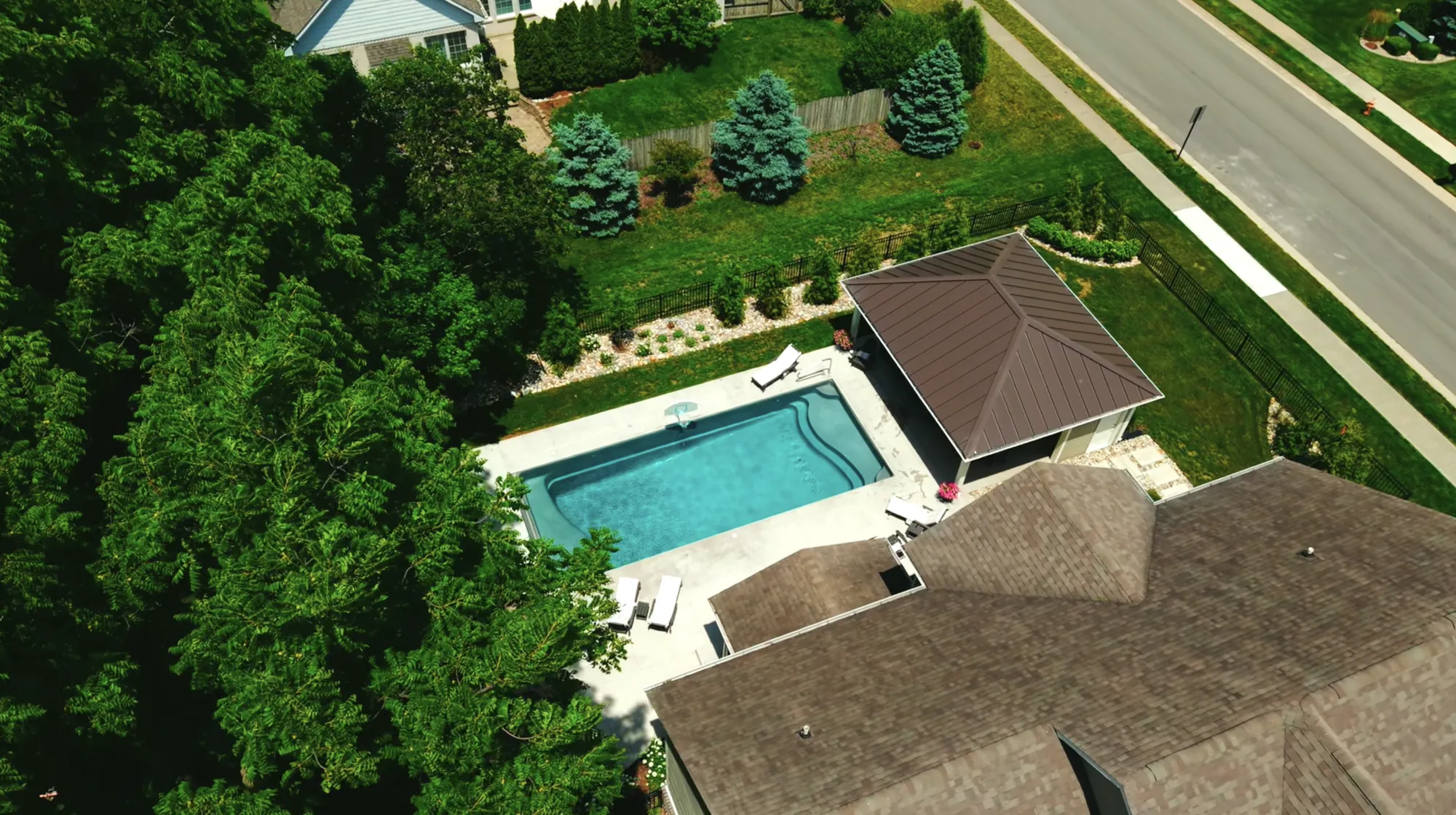 Drone view of the backyard with the pool, pool house and privacy plantings