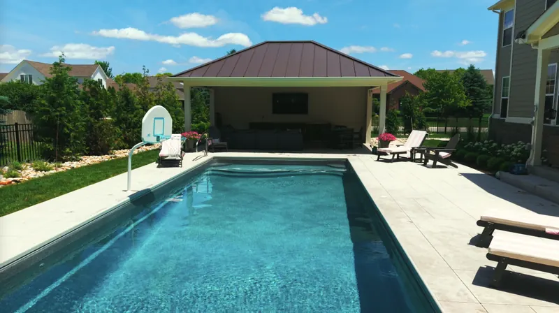 Fiberglass pool and wide pool deck leading to the pool house