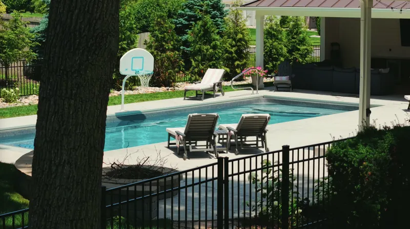 Pool and loungers framed by mature shade trees and evergreen privacy plantings